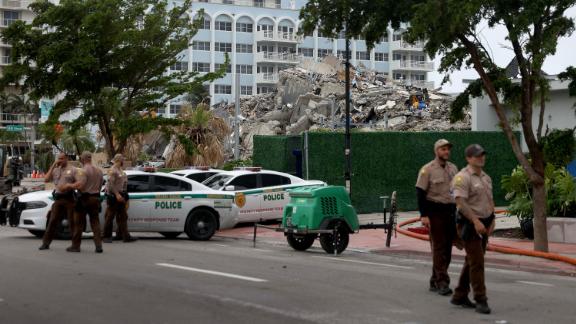 Miami-Dade police officers helping with the search and rescue stand near the completely collapsed 12-story Champlain Towers South on July 6, 2021 in Surfside, Florida. 