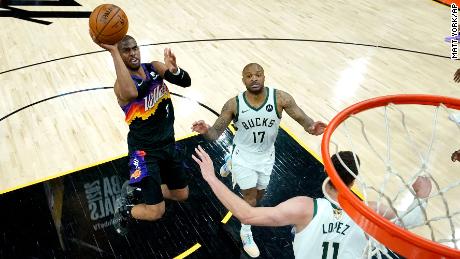 Phoenix Suns guard Chris Paul (3) shoots as Milwaukee Bucks forward P.J. Tucker (17) and center Brook Lopez (11) defend during the first half of Game 5 of basketball&#39;s NBA Finals, Saturday, July 17, 2021, in Phoenix.