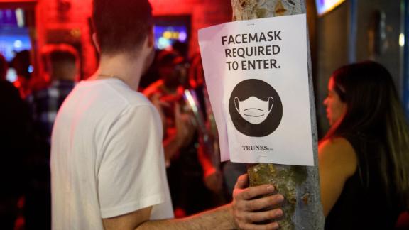 Face mask signage is displayed outside the Trunks bar after midnight early Sunday morning in West Hollywood, California, alerting patrons masks are again required by the county indoors. 