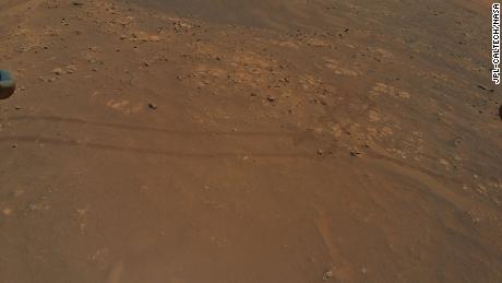 Vrtulník Ingenuity letí paralelně s Perseverance Rover, když jede po povrchu Marsu - o čemž svědčí stopy roveru zachycené kamerou vrtulníku 5. července.