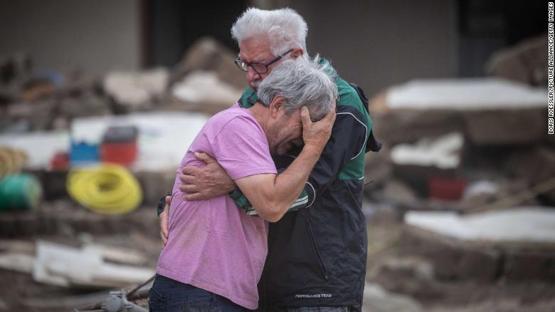 Two brothers embrace Monday, July 19, in front of their parents' home, which was destroyed by flooding in Altenahr, Germany.