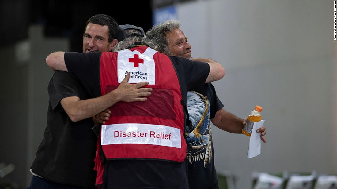 Men hug a member of the Red Cross at a Bootleg Fire evacuation center in Klamath Falls, Oregon.