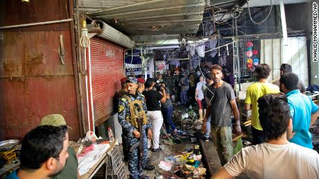 People and security forces gather at the site of a bombing in Wahailat market in Sadr City, Iraq, Monday, July 19, 2021.