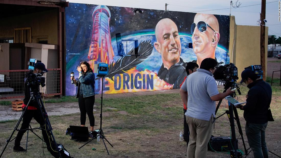 Reporter Celina Quintana Ortiz prepares to go live from Van Horn on Tuesday in front of a mural depicting Jeff and Mark Bezos.