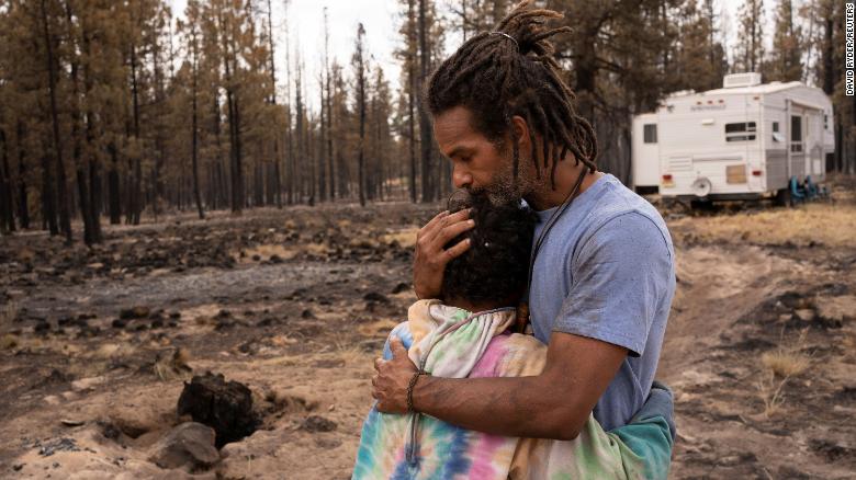 Nicolas Bey, 11, hugs his father, Sayyid Bey, on Monday, July 19, near a donated trailer they are using after their home was burned in the Bootleg Fire near Beatty, Oregon.