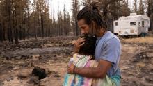 Nicolas Bey, 11, hugs his father, Sayyid Bey, on Monday, July 19, near a donated trailer they are using after their home was burned in the Bootleg Fire near Beatty, Oregon.