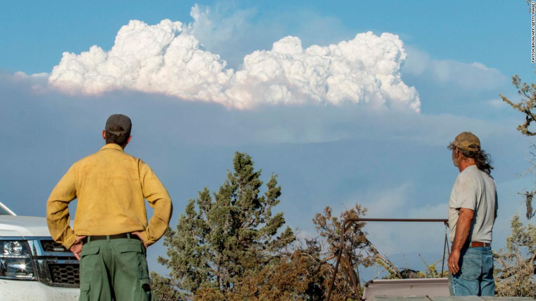 Fire Mitigation and Education Specialist Ryan Berlin (L) and Bob Dillon watch the Bootleg Fire smoke cloud from Dillon&#39;s home in Beatty, Oregon, on July 16, 2021.
