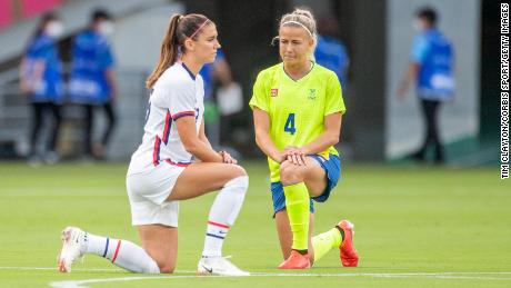 Alex Morgan of the US and Hanna Glas of Sweden take a knee before the start of their match.