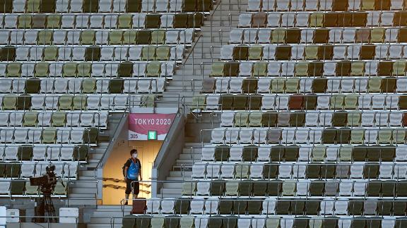 A volunteer is seen in the mostly empty stadium on Friday. Organizers said only 950 VIPs would be present in a stadium that can seat nearly 70,000 people.