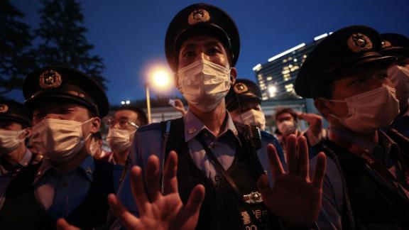A police officer gestures toward a small group of people who were protesting the Olympics outside the stadium on Friday. A significant portion of the Japanese public <a href=