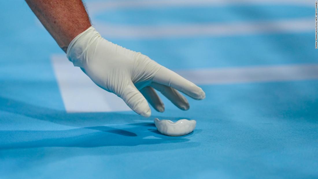 A staff member picks up the mouthguard of Great Britain&#39;s Peter McGrail during a boxing match on July 24.