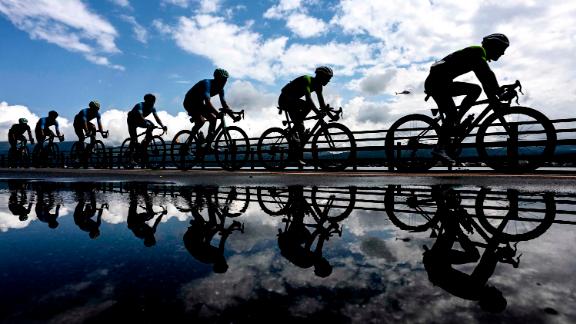 Competitors are reflected in a puddle during the men's cycling road race at Fuji International Speedway, in Tokyo on July 24. <a href=