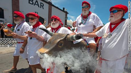 Ernest Hemingway look-alikes push a fake bull with smoke emanating from its nostrils during the &quot;Running of the Bulls&quot; Saturday in Key West, Florida.