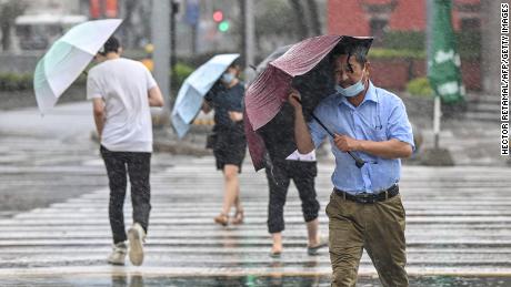 People cross the street in the wind and rain in Ningbo on July 25, as Typhoon In-Fa hits China's east coast.