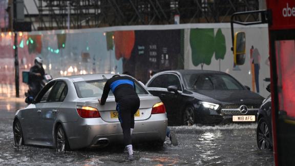 A car is pushed through floodwaters in London's Nine Elms district.