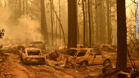 Burned-out vehicles smolder on a property during the Dixie Fire in the Indian Falls area of ​​unincorporated Plumas County.