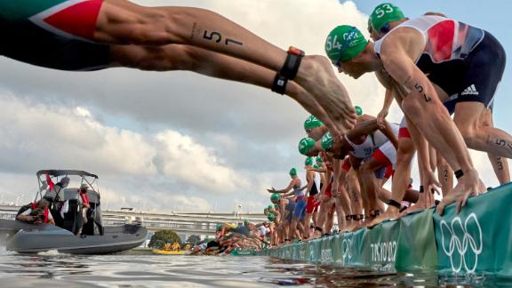 Athletes dive into the water at the start of the men's triathlon on July 26. A broadcast boat prevented all swimmers from starting, <a href=
