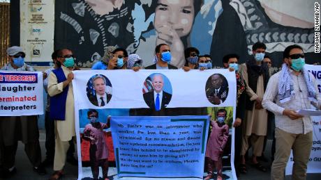 On this June 25, 2021 photo, former Afghan interpreters hold posters during a protest against the US government in front of the US Embassy in Kabul, Afghanistan.  The Biden government says it will evacuate about 2,500 Afghans who worked for the U.S. government and their families to a military base in Virginia pending the approval of their visas. 