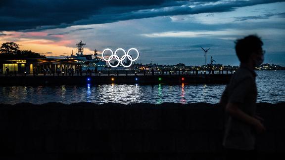 A man in Yokohama, Japan, walks past the Olympic rings lit up at dusk on July 27.