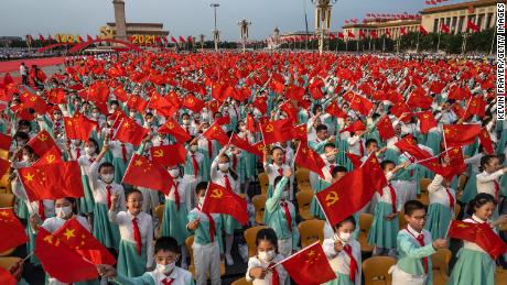 Chinese students wave party and national flags at a ceremony marking the 100th anniversary of the Communist Party at Tiananmen Square on July 1, 2021, in Beijing.