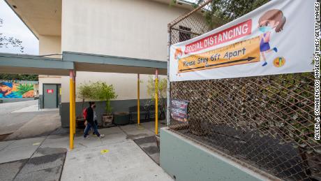 First grade student Daniel Cano, 5, and his mom, Sonia Cano, walk past Covid-19 safety precaution/ social distancing and hand washing signs at a L.A. Unified &quot;meet and greet&quot; with its medical advisors.