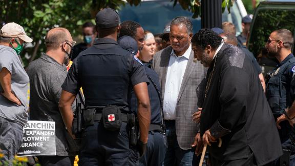 Rev. Jesse Jackson, second from right, and Rev. William Barber II, second from left, stand in front of the Hart Senate Office building in Washington, DC on June 23, blocking the street.
