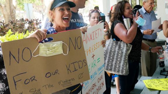 Joann Marcus of Fort Lauderdale, left, cheers as she listens to the Broward School Board's emergency meeting, Wednesday, July 28, 2021, in Fort Lauderdale, Fla. A small but vocal group spoke vehemently against masks, saying their personal rights were being eroded and their children were suffering socially. (AP Photo/Marta Lavandier)