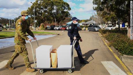 Austrālijas Aizsardzības spēku un Jaundienvidvelsas policijas locekļi 2. augustā ielādē pārtikas pakas piegādei cilvēkiem, kas atrodas apcietinājumā Prairiewood Leisure Center Sidnejā.