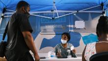 People sign up for vaccinations at a mobile clinic in Brooklyn. New York City will soon require proof of vaccination for indoor dining and gyms, in an effort to curtail a third wave of infections.
