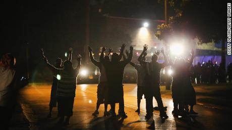 With their hands raised, residents gather at a police line as the neighborhood is locked down following skirmishes on August 11, 2014 in Ferguson, Missouri. Police responded with tear gas as residents and their supporters protested the shooting by police of an unarmed black teenager named Michael Brown who was killed Saturday in this suburban St. Louis community. 