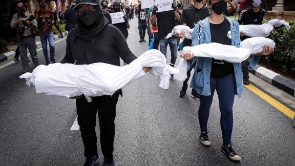 Protesters hold fake corpses during a demonstration near Independence Square in Kuala Lumpur, demanding the resignation of the prime minister over his handling of the coronavirus pandemic.