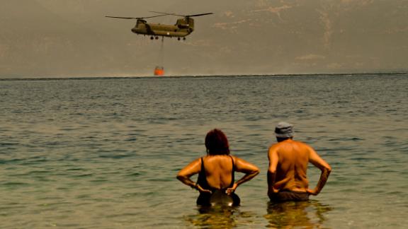 Local residents watch as a Greek army Chinook helicopter collects water to tackle a wildfire near the village of Lambiri, Greece, on Sunday, August 1.