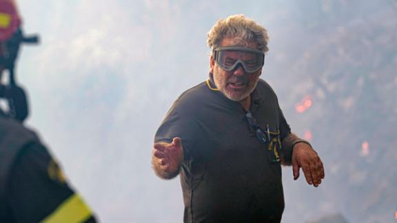 A firefighter talks to his colleague as they work to put out fires in Cuglieri, on the Italian island of Sardinia, on Monday, July 26.