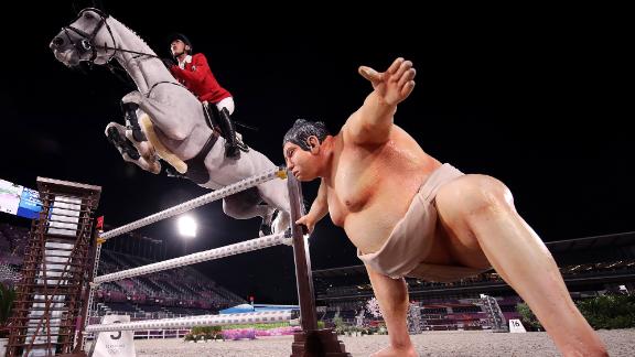 A statue of a sumo wrestler is seen near an obstacle as Japan's Koki Saito, aboard Chilensky, competes in jumping qualifiers on August 4. Riders said the lifelike statue <a href=