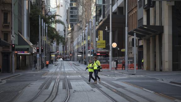 أصحاب المتاجر يعبرون شارعًا فارغًا تقريبًا في سيدني ، أستراليا ، في 2 أغسطس.