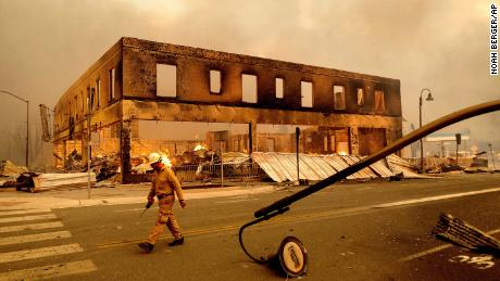 A firefighter passes the Sierra Lodge on Wednesday as the Dixie Fire burns through Greenville.