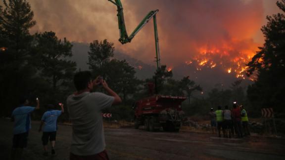 People watch an advancing fire that rages around Cokertme village, near Bodrum, Turkey, on August 2.