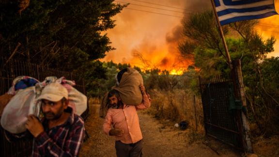 People move belongings to safety as a forest fire rages in a wooded area north of Athens, Greece, on August 5.