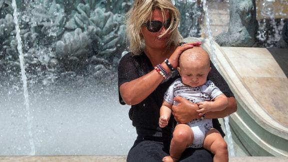 A woman pours water over a baby's head at a fountain in Skopje, Republic of North Macedonia, as temperatures reached over 40 degrees Celsius (104 degrees Fahrenheit) on Monday, August 2. 