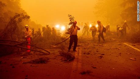 Firefighters battling the Dixie Fire clear Highway 89 after a burned tree fell across the roadway in Plumas County, California, on Friday, August 6.