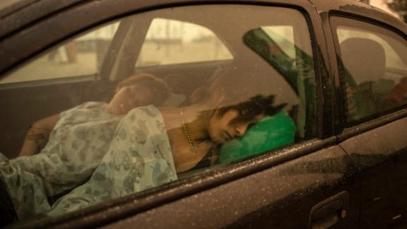 People sleep in a car near the beach in Pefki village, as wildfires rage on the island of Evia.
