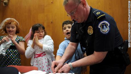 Capitol Police Officer Howard Liebengood fingerprints a child during &quot;Kid Safety Day,&quot; held in Washington DC, in April 2008. Liebengood died by suicide after the US Capitol riot in January 2021.