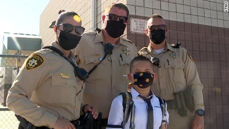 Las Vegas police officers stand with Noah Swanger outside his school on the first day of classes on Monday, August 9.