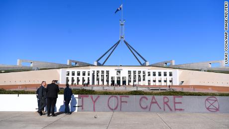 Workers cover the slogan &#39;Duty of Care&#39; after an Extinction Rebellion protest outside Parliament House, in Canberra, Monday, August 10.