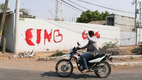 A motorist passes by a wall with a graffiti of the Jalisco New Generation Cartel (CJNG) in Michoacan state, Mexico, on April 23.
