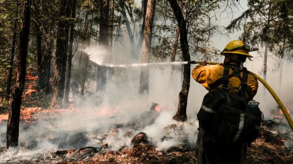 A firefighter works to extinguish a controlled burn, a preventative measure, to protect a home in Greenville, California, on Monday, August 9.