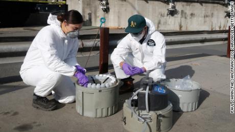 Gabriela Esparza and Zach Wu, wastewater control inspectors with EBMUD, cap 24 separate bottles while retrieving collection equipment and the samples in Oakland, California, in July 2020. The samples are sent to labs to detect coronavirus in the sewage.