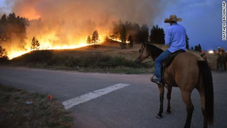 Rowdy Alexander watches from atop his horse as a hillside burns on the Northern Cheyenne Indian Reservation near Lame Deer, Montana, on August 11, 2021