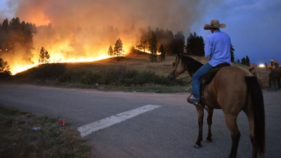 Rowdy Alexander watches from atop his horse as a hillside burns on the Northern Cheyenne Indian Reservation near Lame Deer, Montana, on August 11, 2021