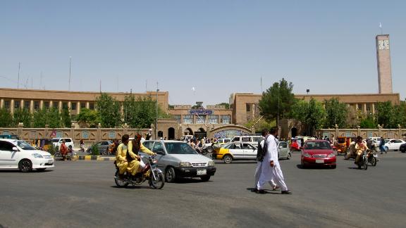 Pedestrians and motorists travel near the Herat provincial official office, Saturday, after the province was taken by the Taliban several days before.